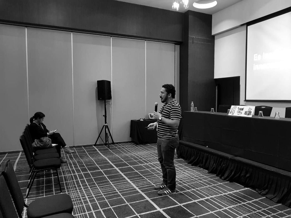 Chris Fawcett presentando frente a una pantalla en una sala de conferencias